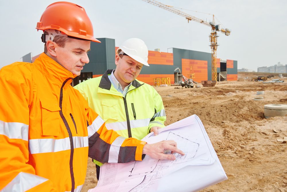 an employee wearing an orange safety coat talking to a safety leader about their project